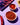 Bowl of red chili powder with dried chili slices on a purple surface